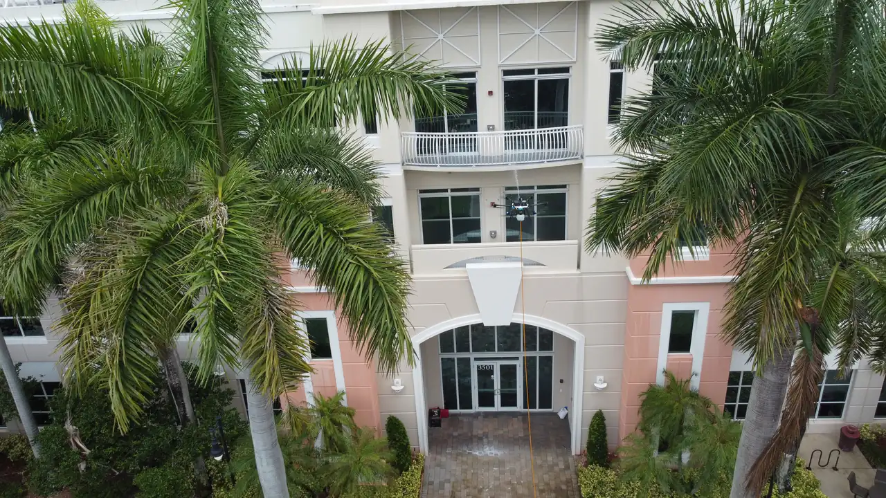 Building Cleaning Without Scaffolding — Miami Drone Facade Wash Aerial view of a Miami commercial building entrance cleaned by drone without scaffolding